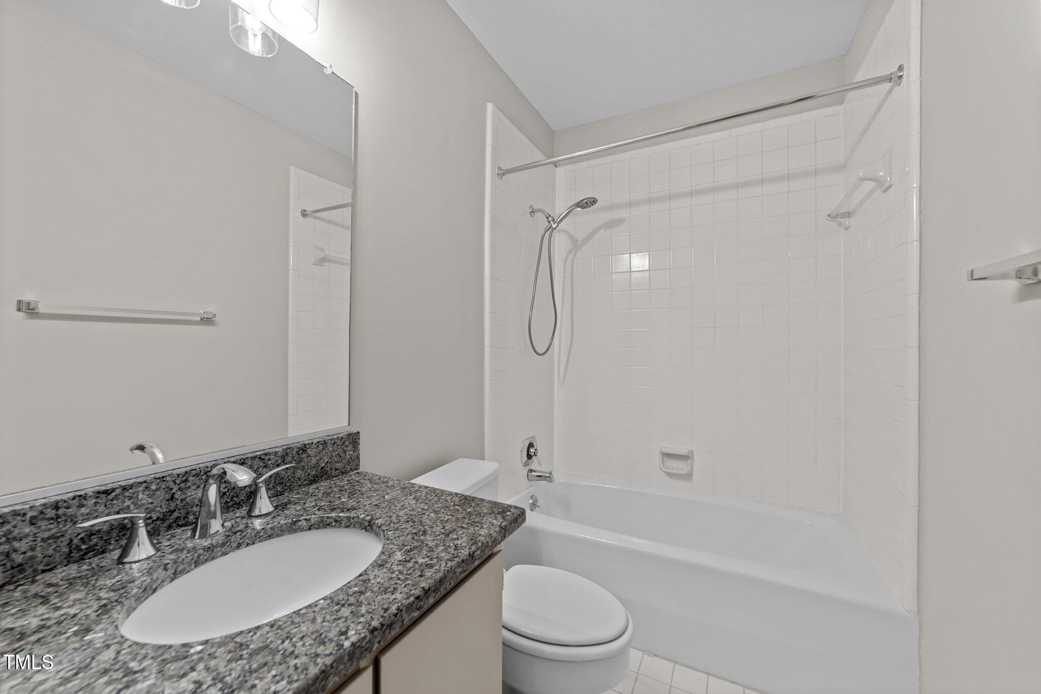 243 New Bern Place, Unit 301 Raleigh, NC 27601 - Photo 21 of 31 a bathroom with a granite countertop sink a toilet and shower