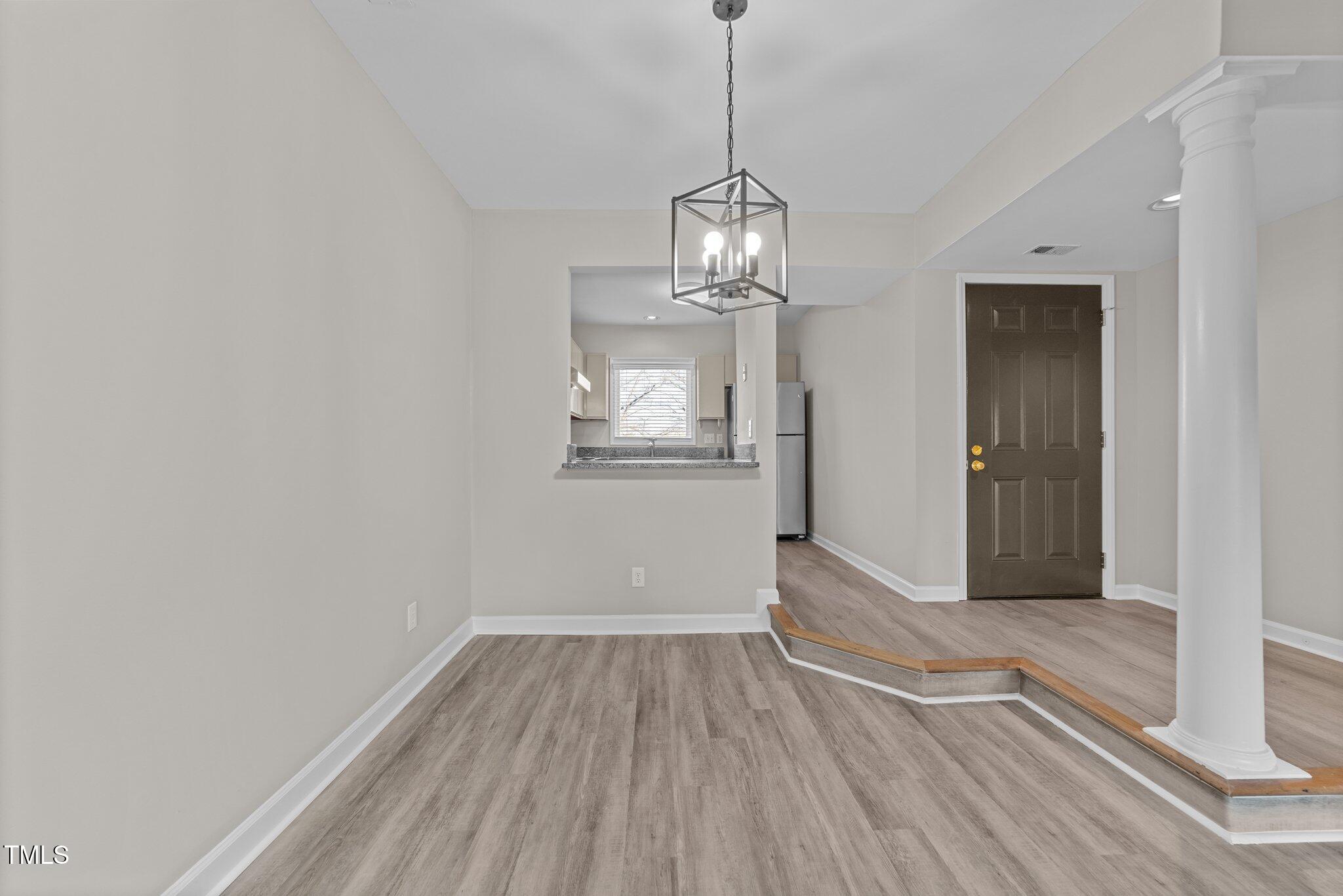 243 New Bern Place, Unit 301 Raleigh, NC 27601 - Photo 9 of 31 a view of empty room with wooden floor and kitchen