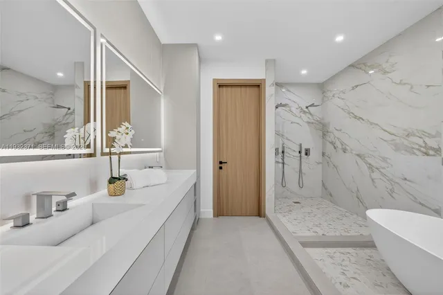 a bathroom with a tub a sink and a large mirror