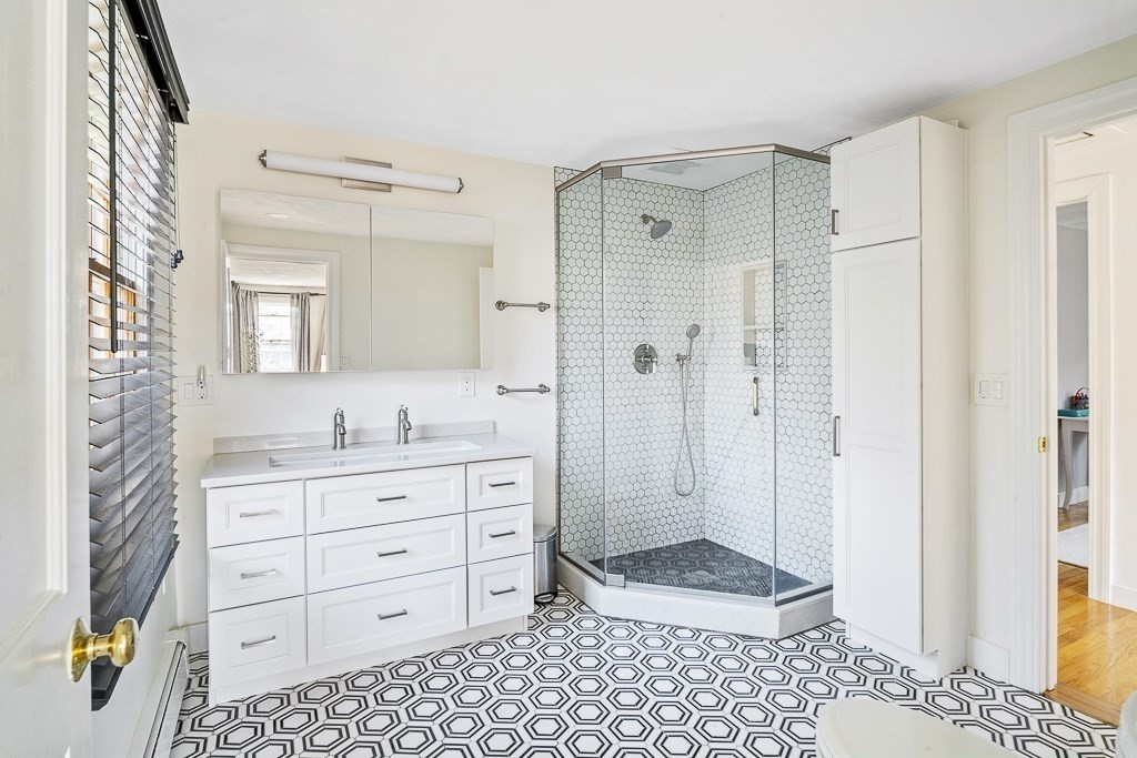 28 Longmeadow Road Arlington, MA 02474 - Photo 18 of 25 a bathroom with a granite countertop sink a mirror a vanity and a shower