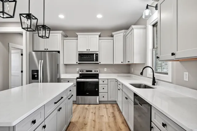 a kitchen with stainless steel appliances a sink dishwasher a refrigerator and cabinets with wooden floor
