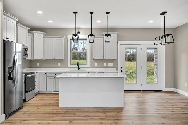 a kitchen with stainless steel appliances granite countertop a sink a refrigerator and a wooden floor