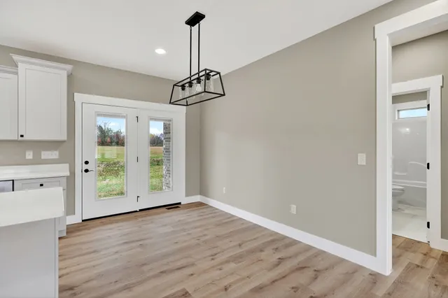 a view of empty room with wooden floor and kitchen view