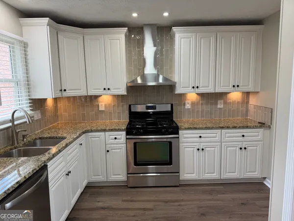 a kitchen with granite countertop a stove sink and cabinets