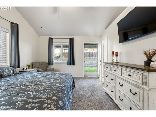 a bedroom with a bed and a flat tv screen on dresser