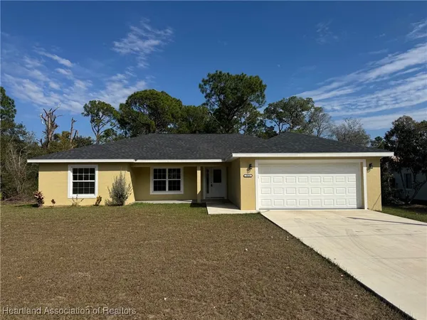 front view of house with yard and trees in the background