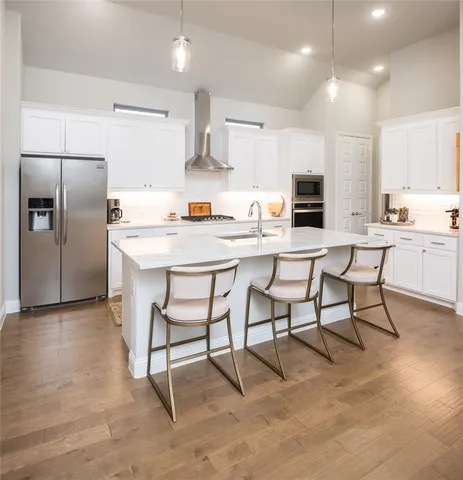 a kitchen with stainless steel appliances kitchen island granite countertop a table chairs microwave and sink