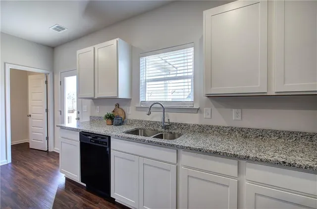 a kitchen with granite countertop white cabinets and a sink