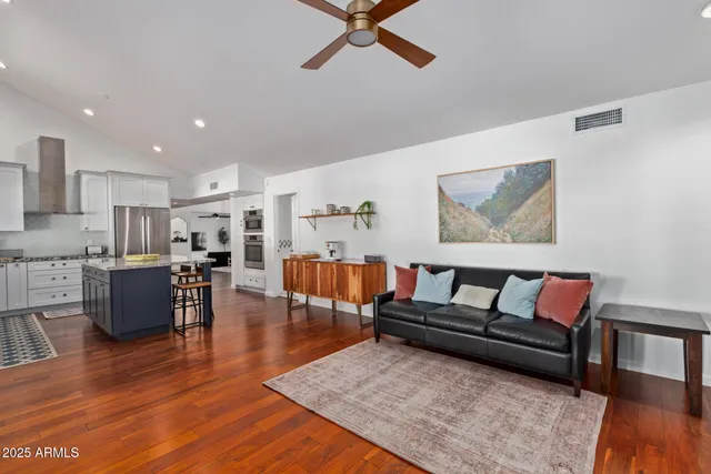 a living room with furniture kitchen view and a wooden floor