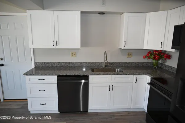 a kitchen with granite countertop white cabinets and black appliances