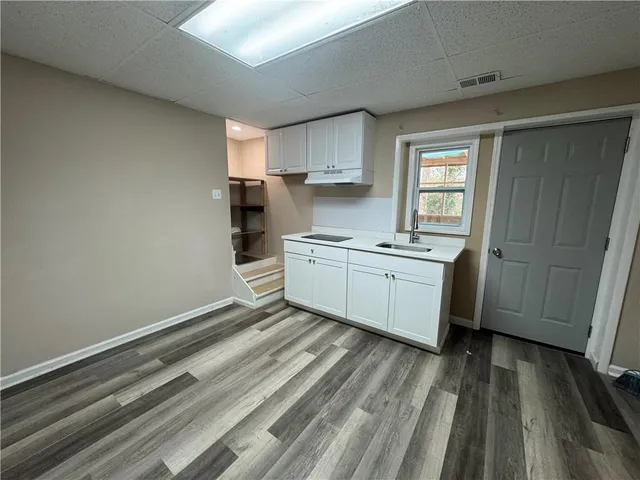a kitchen with a sink a stove cabinets and wooden floor