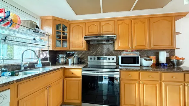 a kitchen with stainless steel appliances granite countertop a stove a sink and a microwave
