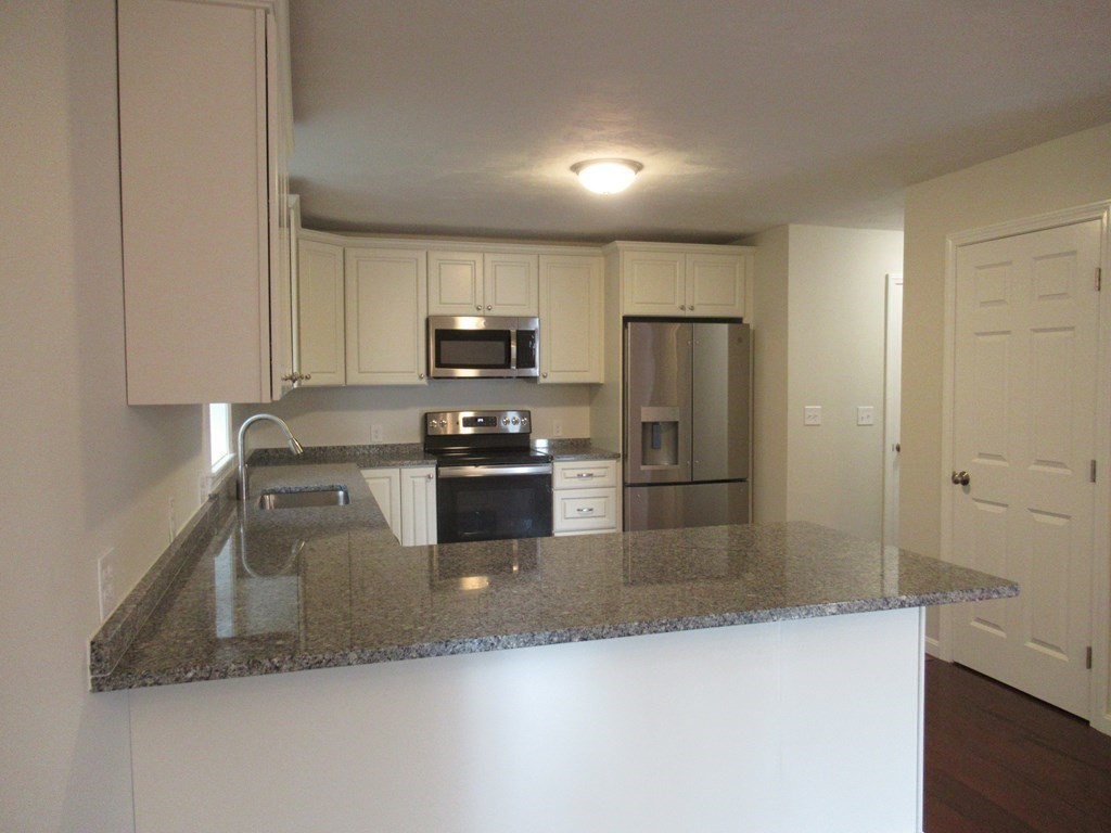 16 Farnum Street Uxbridge, MA 01569 - Photo 12 of 27 a kitchen with stainless steel appliances granite countertop a refrigerator a stove and a sink with wooden floor