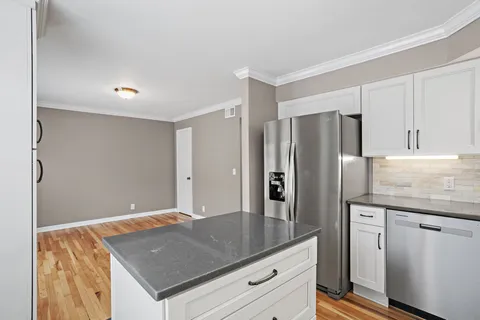 a kitchen with stainless steel appliances granite countertop a refrigerator a sink and white cabinets