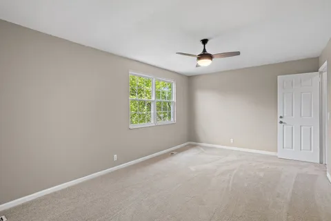 an empty room with ceiling fan and window