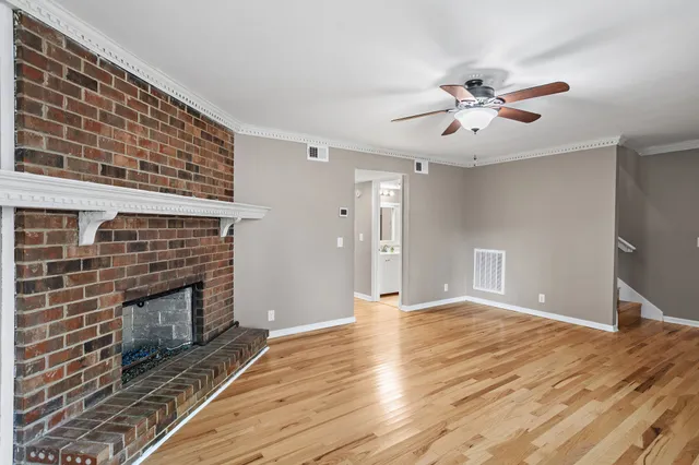 a view of an empty room with a fireplace and a fan