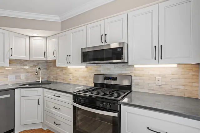 a kitchen with granite countertop white cabinets and stainless steel appliances