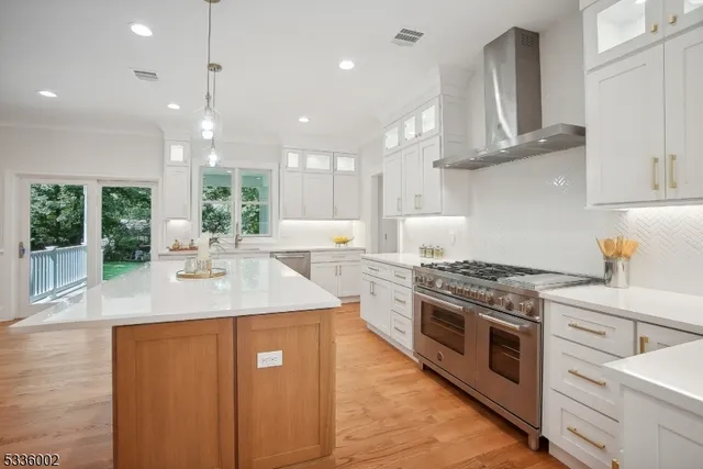 a kitchen with stainless steel appliances granite countertop a sink a stove and a wooden floors