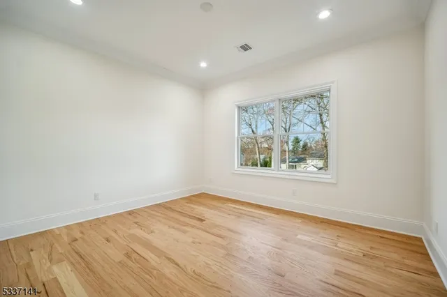 an empty room with wooden floor and window