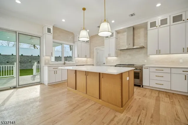 a large kitchen with granite countertop a stove a sink and white cabinets with wooden floor