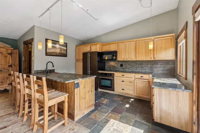 a kitchen with granite countertop a stove a sink and a refrigerator