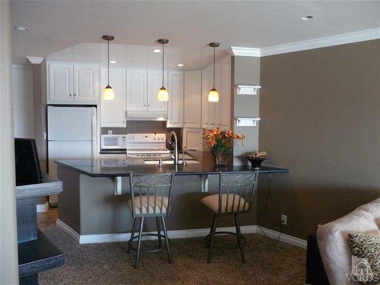2901 Peninsula Road, Unit 247 Oxnard, CA 93035 - Photo 7 of 30 a kitchen with a table chairs and a refrigerator