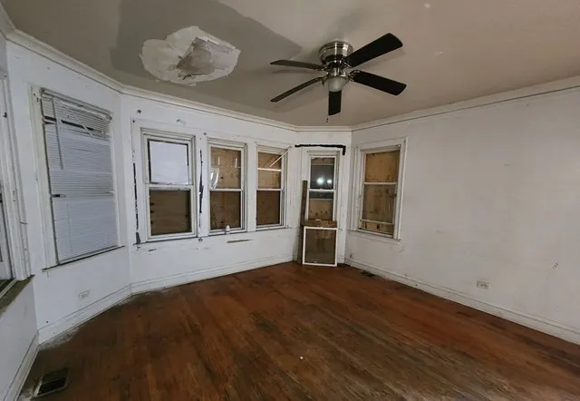 a view of an empty room with a window and wooden floor