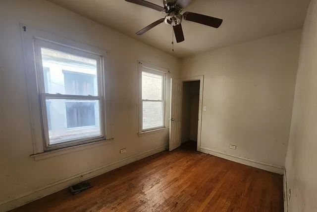 a view of empty room with wooden floor and fan