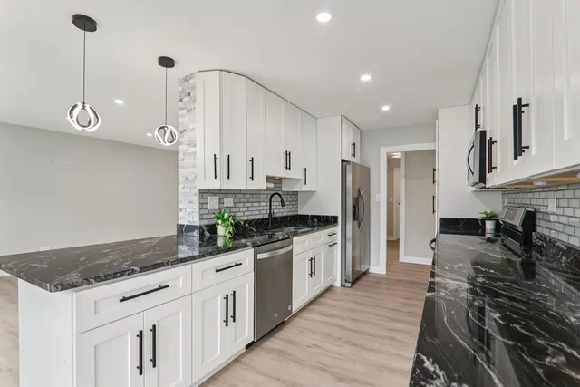 a kitchen with stainless steel appliances granite countertop a stove a sink and a refrigerator