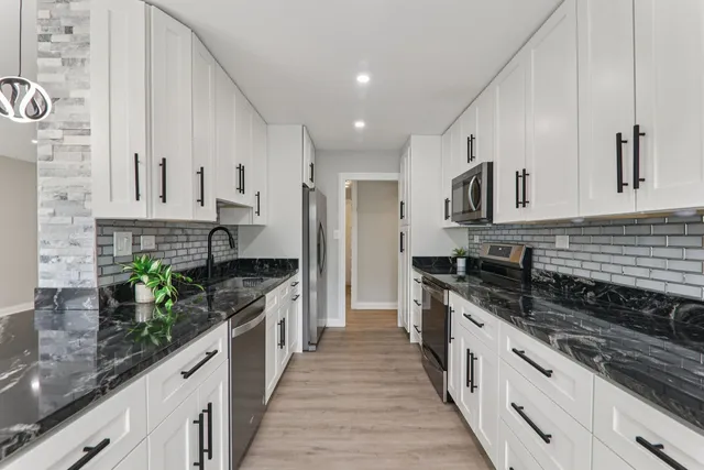 a large kitchen with stainless steel appliances granite countertop a lot of counter space and wooden floors