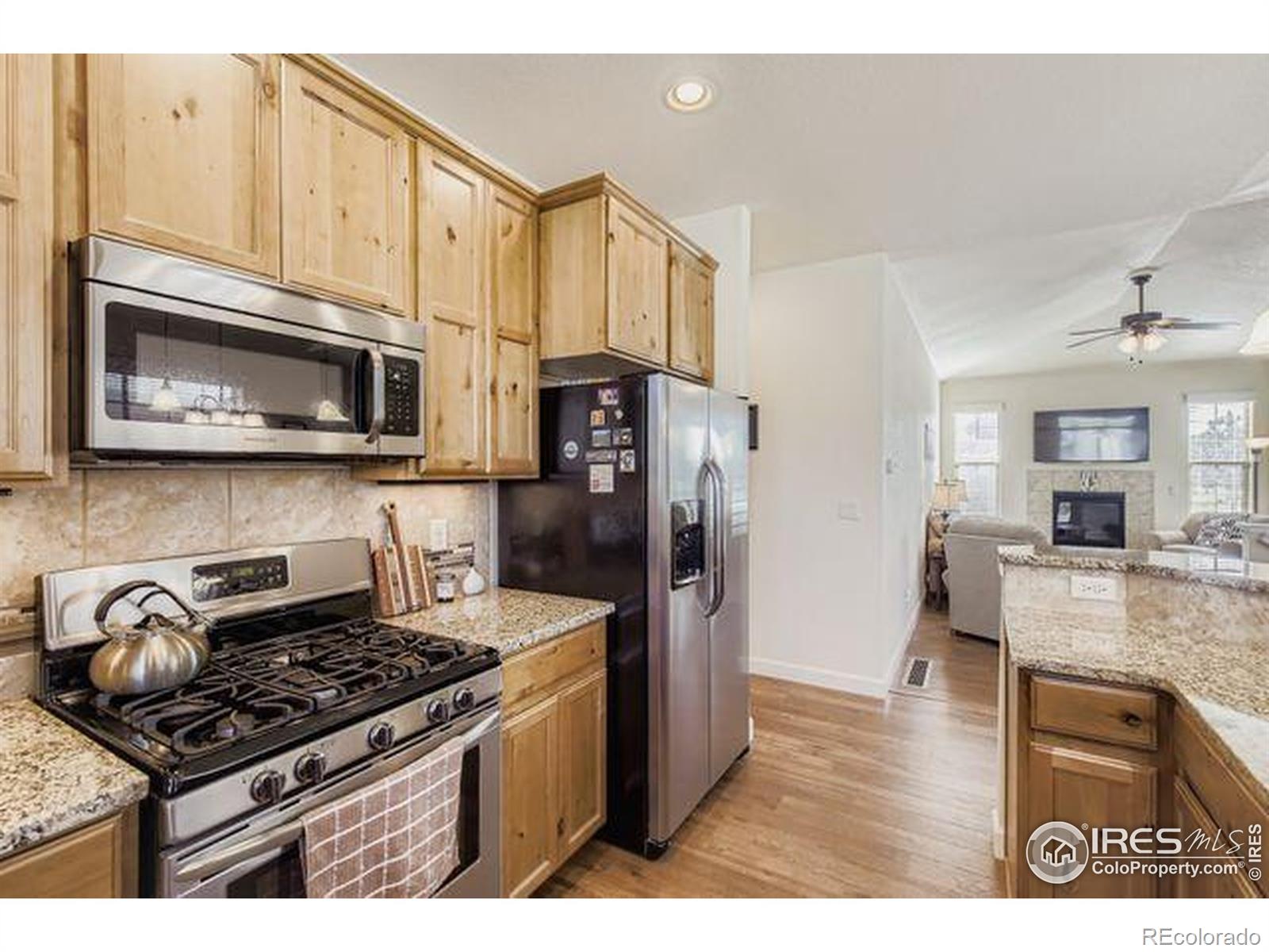 3453 Rhea Drive Loveland, CO 80537 - Photo 13 of 33 a kitchen with stainless steel appliances granite countertop a stove a refrigerator and a microwave