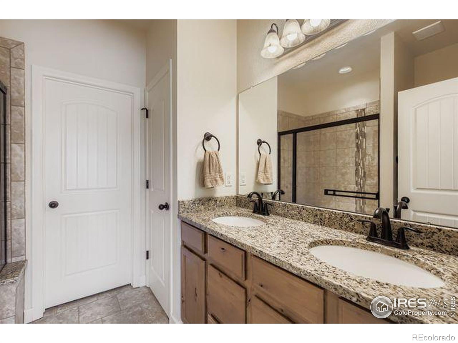 3453 Rhea Drive Loveland, CO 80537 - Photo 17 of 33 a bathroom with a granite countertop double vanity sink and a mirror
