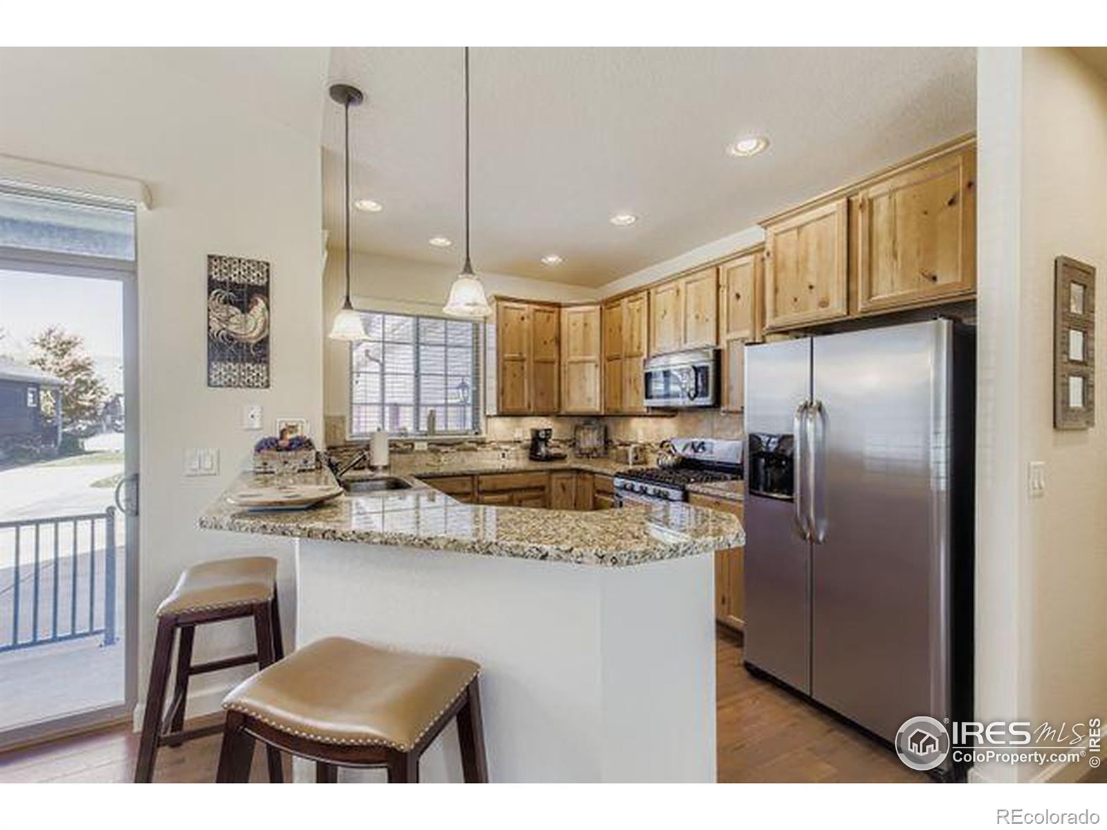 3453 Rhea Drive Loveland, CO 80537 - Photo 10 of 33 a kitchen with stainless steel appliances granite countertop a sink a stove a refrigerator and island with wooden floor