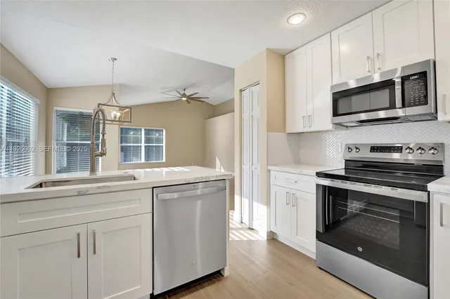 a kitchen with white cabinets stainless steel appliances and sink