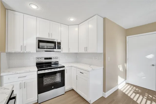 a kitchen with white cabinets and stainless steel appliances