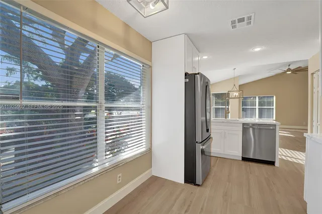 a view of a refrigerator in kitchen and an empty room