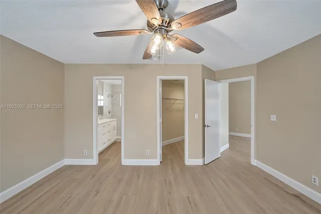 an empty room with wooden floor closet and windows