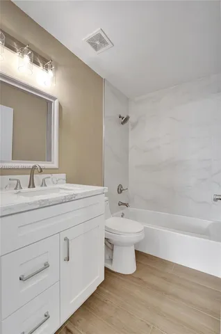 a bathroom with a double vanity sink a toilet and bathtub