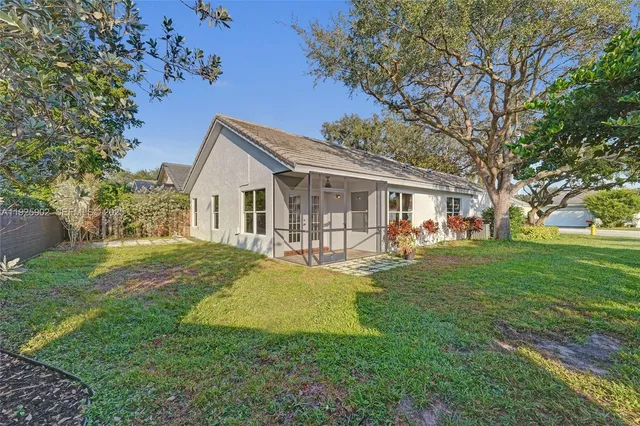 a view of a house with a yard and a large tree