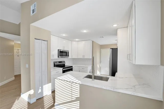 a kitchen with stainless steel appliances kitchen island granite countertop a refrigerator and a sink
