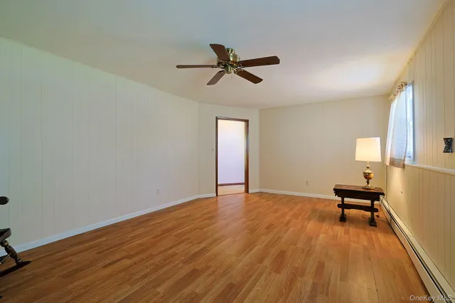 a view of empty room with wooden floor and fan