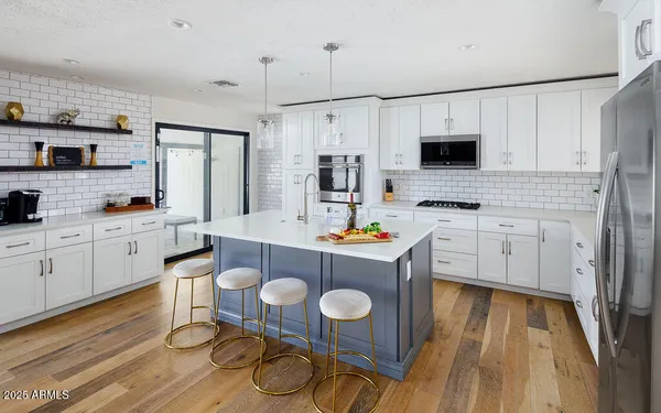 a kitchen with stainless steel appliances a white table and chairs in it