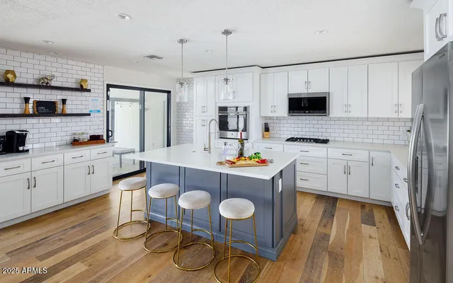 a kitchen with stainless steel appliances a white table and chairs in it