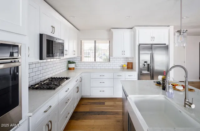 a kitchen with white cabinets and stainless steel appliances