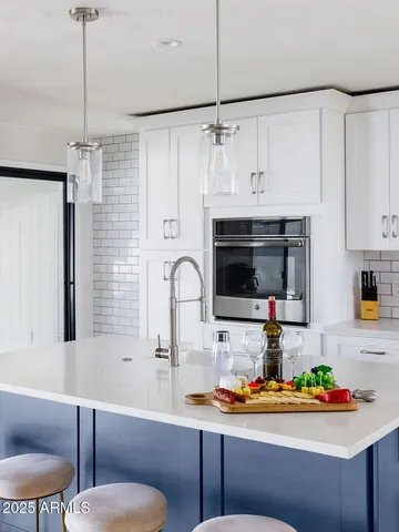 a kitchen with stainless steel appliances a white table chairs and a refrigerator
