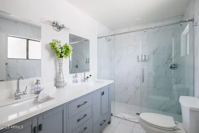 a bathroom with a granite countertop sink a toilet a shower and a mirror