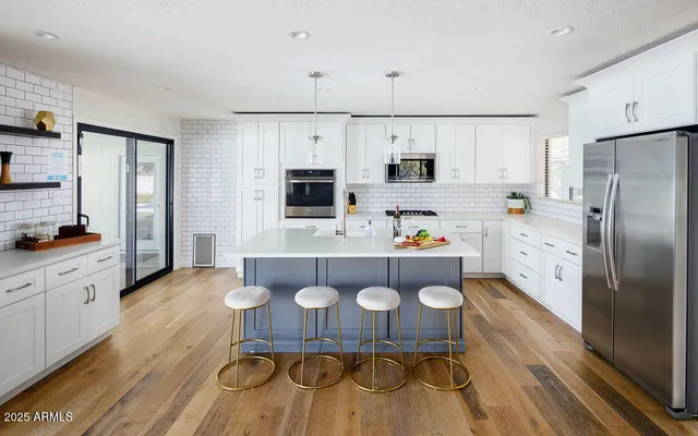 a kitchen with stainless steel appliances a sink a stove a refrigerator cabinets and a dining table