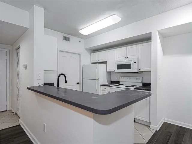 a kitchen with kitchen island granite countertop a sink a stove and refrigerator