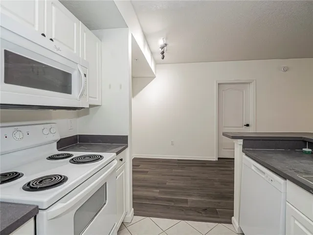 a kitchen with granite countertop cabinets stove top oven and microwave