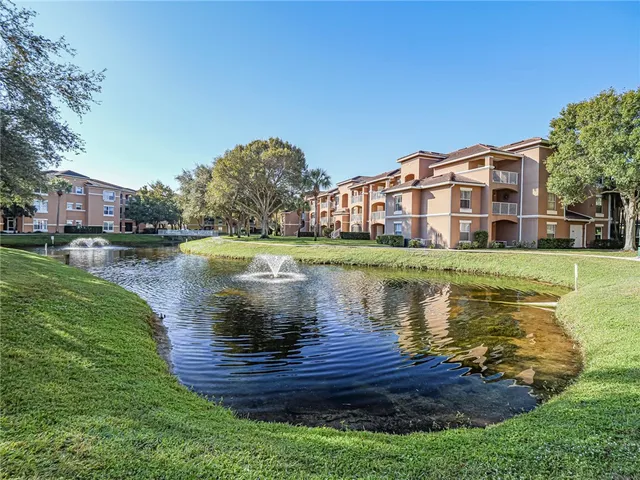 a view of a lake with a big yard and large trees